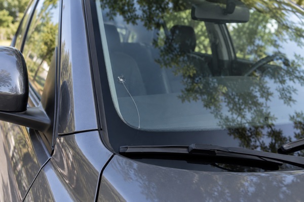 Windshield crack running from a small chip down to the edge of the glass above the wiper